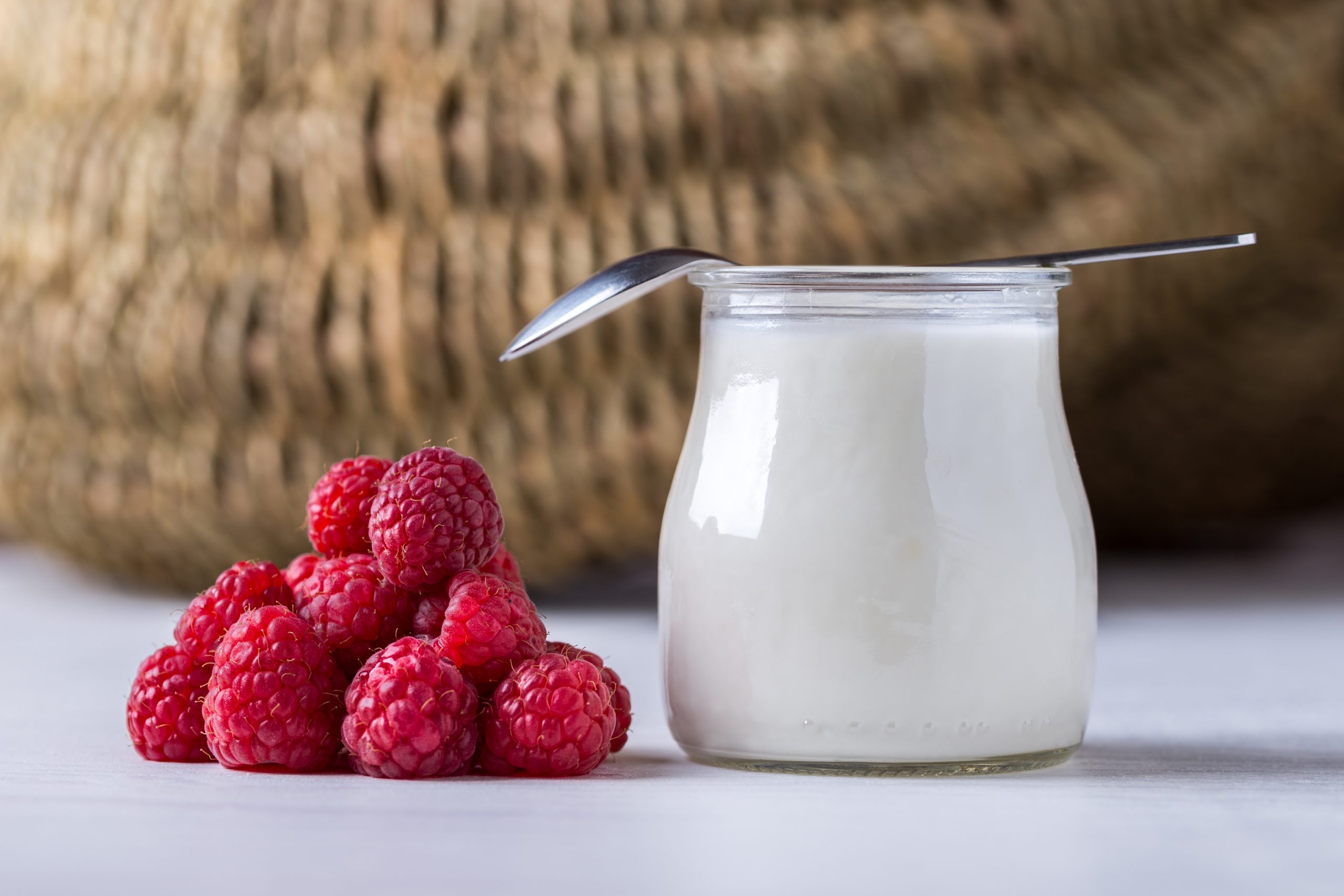 White,Yogurt,With,Raspberries,In,Glass,Bowl,On,White,Table.