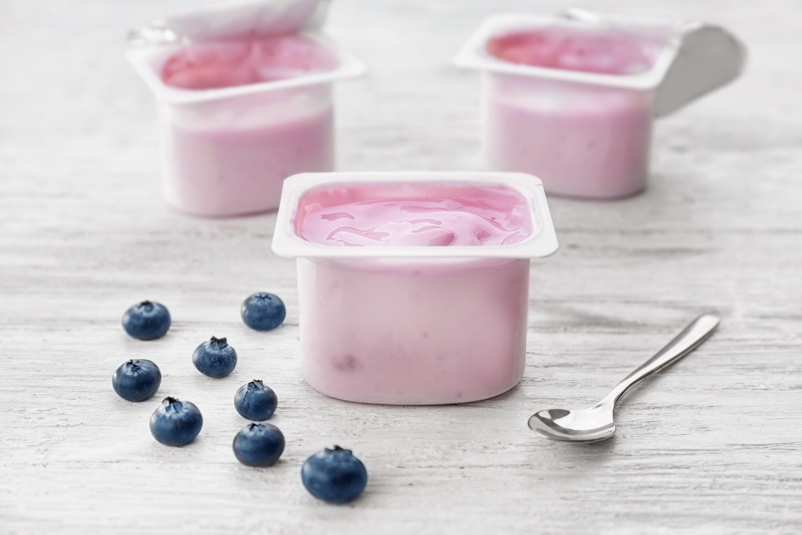 Plastic,Cup,With,Yogurt,And,Blueberries,On,Wooden,Table